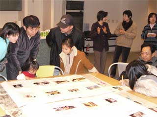 写真： 掲示用台紙に貼られた自慢のペット写真を見る参加者